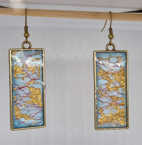 Resin art earrings, blue background with pink and gold lace in bronze tone setting.